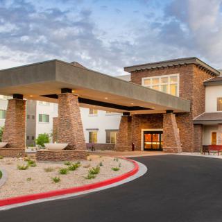 A modern building entrance with a well-maintained driveway and landscaping.