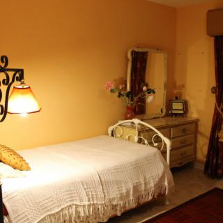 Cozy bedroom with a single bed, warm tones, and decorative elements.