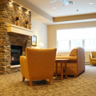 A cozy living room with armchairs and a stone fireplace.