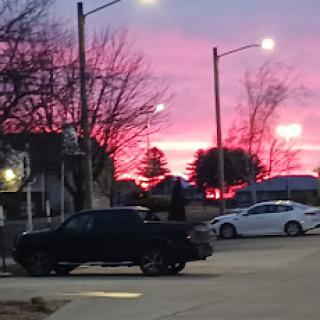 A vibrant sunset paints the sky in shades of pink, casting a beautiful glow over the urban landscape.
