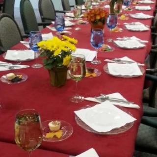 A long dining table set with red tablecloths, flowers, and neatly arranged place settings.