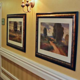 Two framed paintings displayed in a hallway.