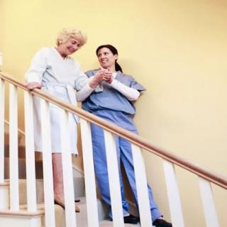 A nurse assists an elderly woman down the stairs, highlighting support and care.