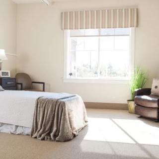 A bright and cozy bedroom with a bed, chair, and a window letting in natural light.