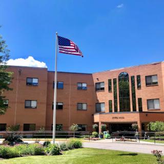 A brick building featuring an American flag flying in front, set against a clear blue sky.