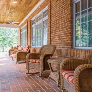 A cozy porch with wicker furniture and brick flooring, perfect for outdoor relaxation.