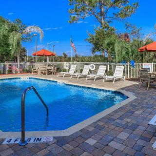An inviting outdoor swimming pool surrounded by lounge chairs and umbrellas under a clear blue sky.
