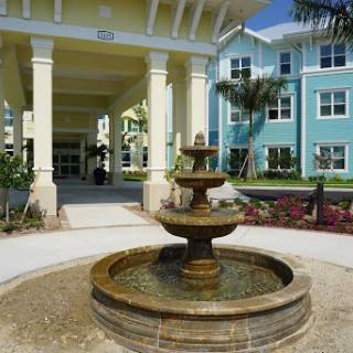 A picturesque view of a fountain with a colorful residential building in the background.