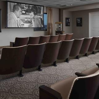 A small theater with vintage cinema seating and a classic film playing on the screen.