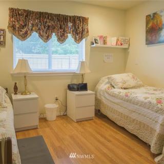 A cozy bedroom with twin beds, nightstands, and decorative curtains.