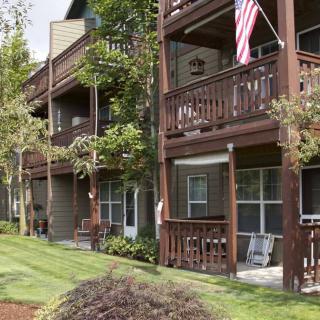 A view of an apartment building with balconies, surrounded by trees and well-maintained landscaping.