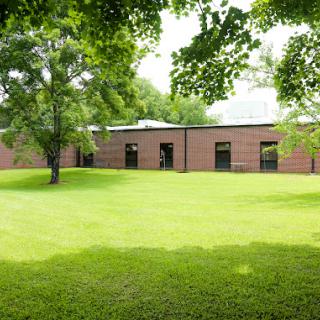 A serene view of a brick building surrounded by lush greenery and trees.