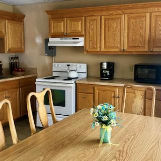 A cozy kitchen featuring wooden cabinets and a dining table adorned with flowers.