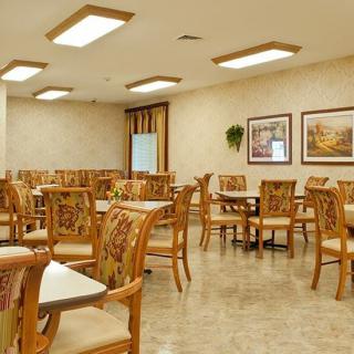 An empty dining room with neatly arranged tables and chairs, decorated with wall paintings.