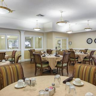 A well-lit dining area with neatly arranged tables and chairs.