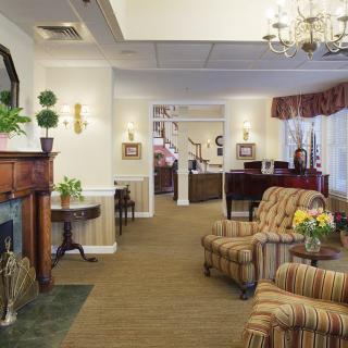 A cozy living room with elegant furnishings, featuring a fireplace and chandelier.