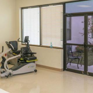 A well-lit gym room with a stationary bike by the window.