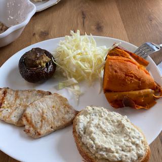 A colorful and healthy plate featuring grilled meat, sweet potato, cabbage salad, and other vegetables.