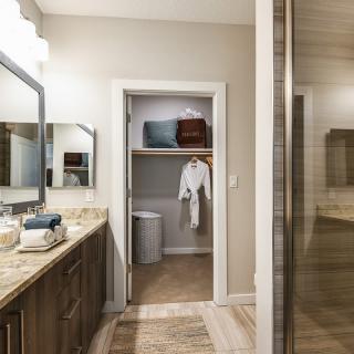 A modern bathroom with a view of the vanity and an open closet containing robes.