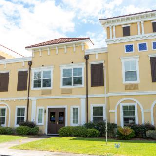 A yellow building with multiple windows and a classic architectural style under a blue sky.