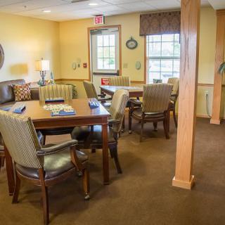 A cozy meeting room with tables and chairs, softly lit by lamps.