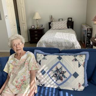 An elderly woman relaxing on a blue sofa in a cozy living space.