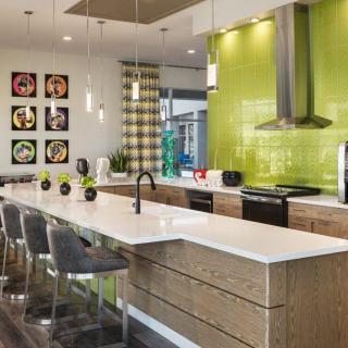 A modern kitchen with a vibrant green backsplash, sleek countertops, and stylish bar stools.