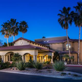 A beautifully lit building surrounded by palm trees at dusk.