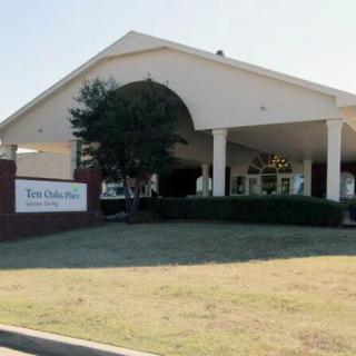 A building entrance with a sign and surrounding greenery.
