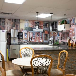 A cozy kitchen and dining area with decorative wall art, a round table with chairs, and modern appliances.