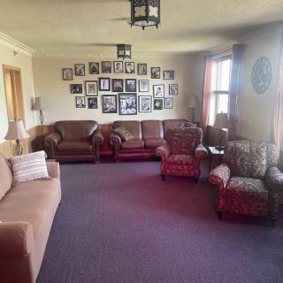 A cozy living room with multiple sofas and armchairs, decorated with a wall of picture frames.