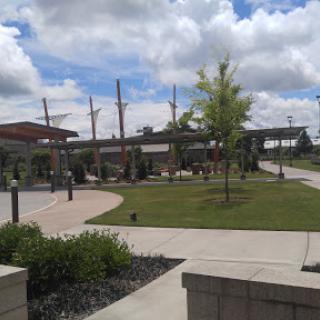 A serene park scene featuring pathways, greenery, and architectural elements under a cloudy sky.