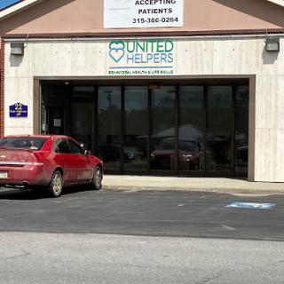 A view of the United Helpers office with a parked red car in front.