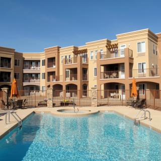 A modern apartment complex with a swimming pool on a sunny day.