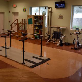 A well-equipped physical therapy room featuring a barre for rehabilitation exercises.