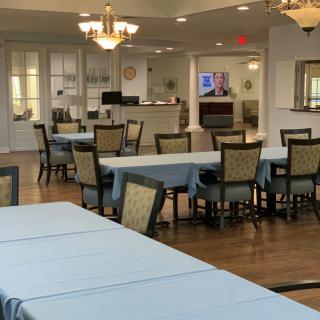 A spacious dining area with tables and chairs set up, featuring elegant chandeliers and a welcoming atmosphere.