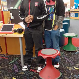 Two students standing in a library, showcasing a modern learning environment.