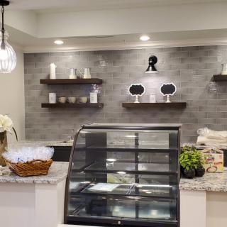A modern bakery counter with an empty display case and decorative shelves.