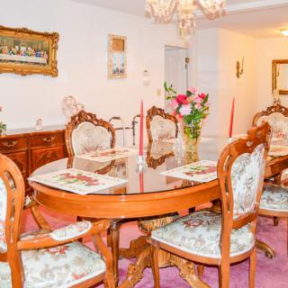 A traditionally styled dining room with antique furniture and a chandelier, featuring a floral arrangement on the table.