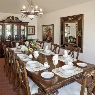 Elegant dining room with a set table, chandelier, and decorative mirror.