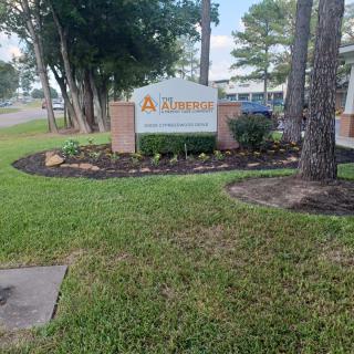 A well-maintained entrance sign surrounded by landscaped greenery and trees.