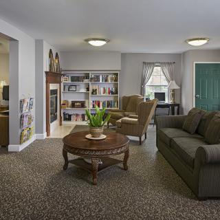 A cozy living room with a sofa, coffee table, bookshelf, and window.