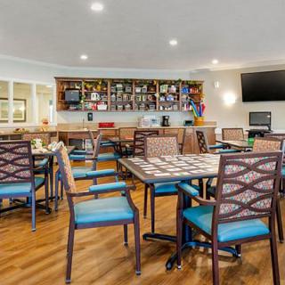 A cozy dining area featuring a bar with various bottles, tables, and chairs arranged neatly.