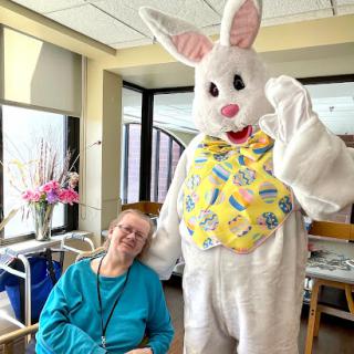 A cheerful Easter celebration featuring a person in a bunny costume with an elderly resident.