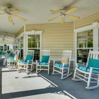 A cozy porch with wooden rocking chairs and ceiling fans, perfect for relaxation in a shaded outdoor setting.