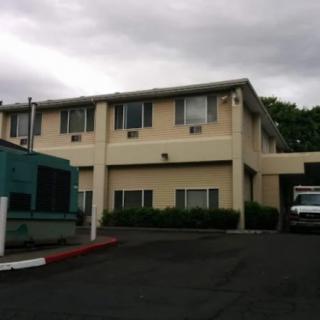 A two-story building with a parking lot in front under a cloudy sky.