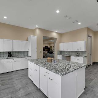 A modern kitchen with white cabinets and granite countertops, featuring a large island and sleek design.
