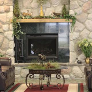 A cozy living room featuring a stone fireplace surrounded by comfortable seating and decorative plants.