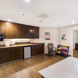 A modern kitchen interior featuring wood cabinetry, a small refrigerator, and artwork on the walls.