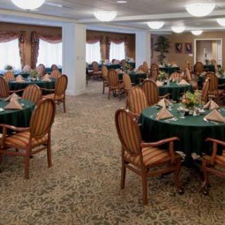 A well-decorated dining room with round tables and upholstered chairs, ready for service.